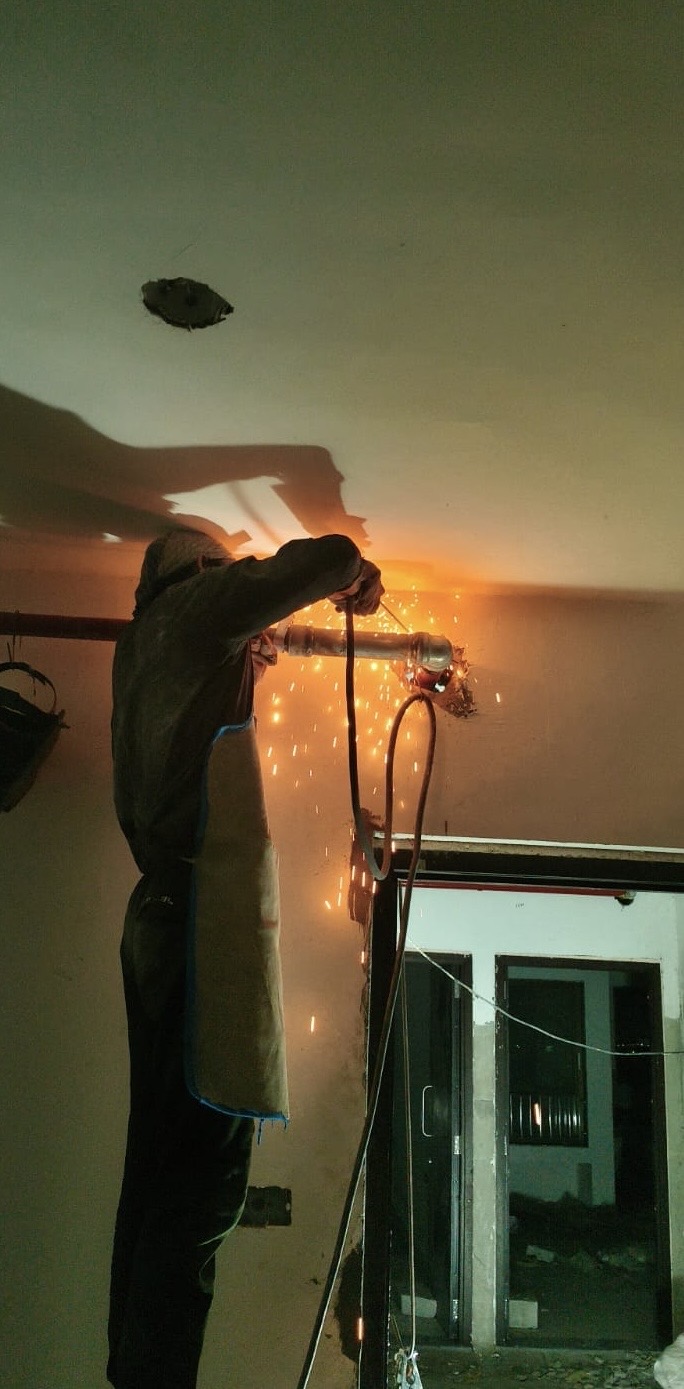 Worker installing overhead fire fighting pipework inside a building