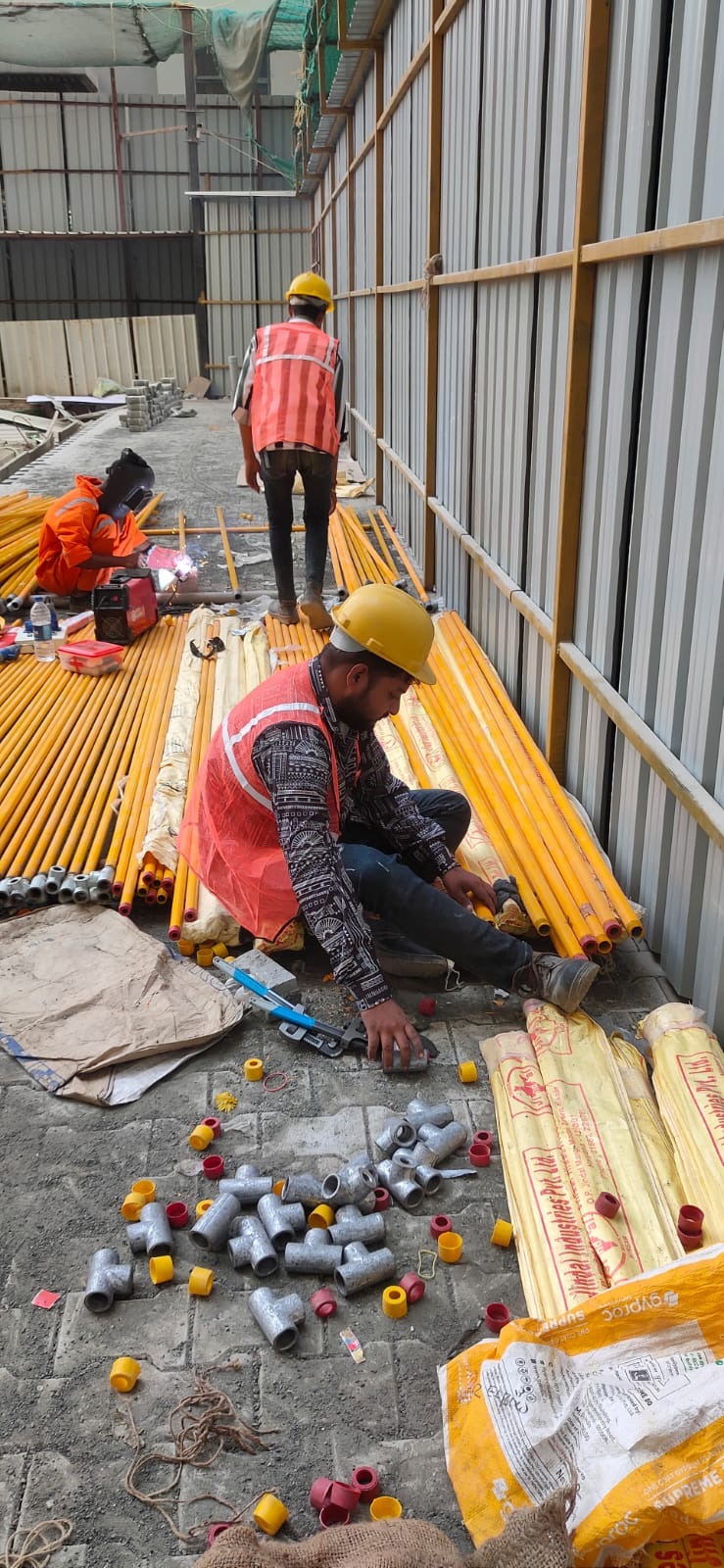 Workers welding and assembling yellow gas pipe sections and fittings
