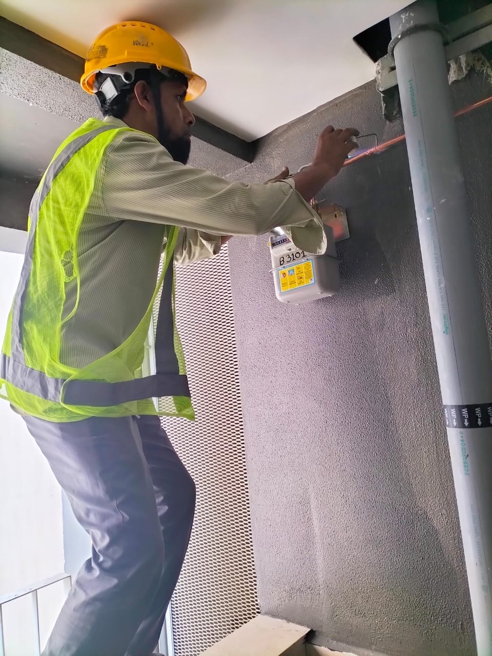 Worker connecting a wall-mounted gas meter and copper pipework
