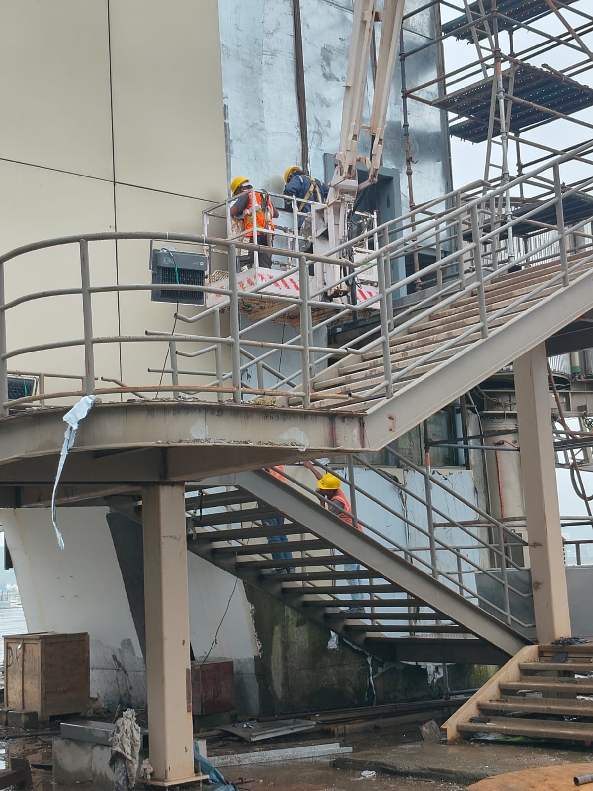 Workers installing exterior facade cladding beside a steel access structure
