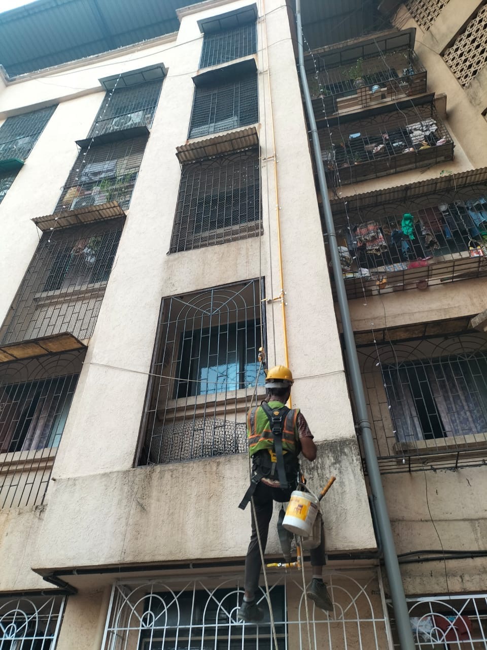Worker installing a vertical gas pipeline on a residential building